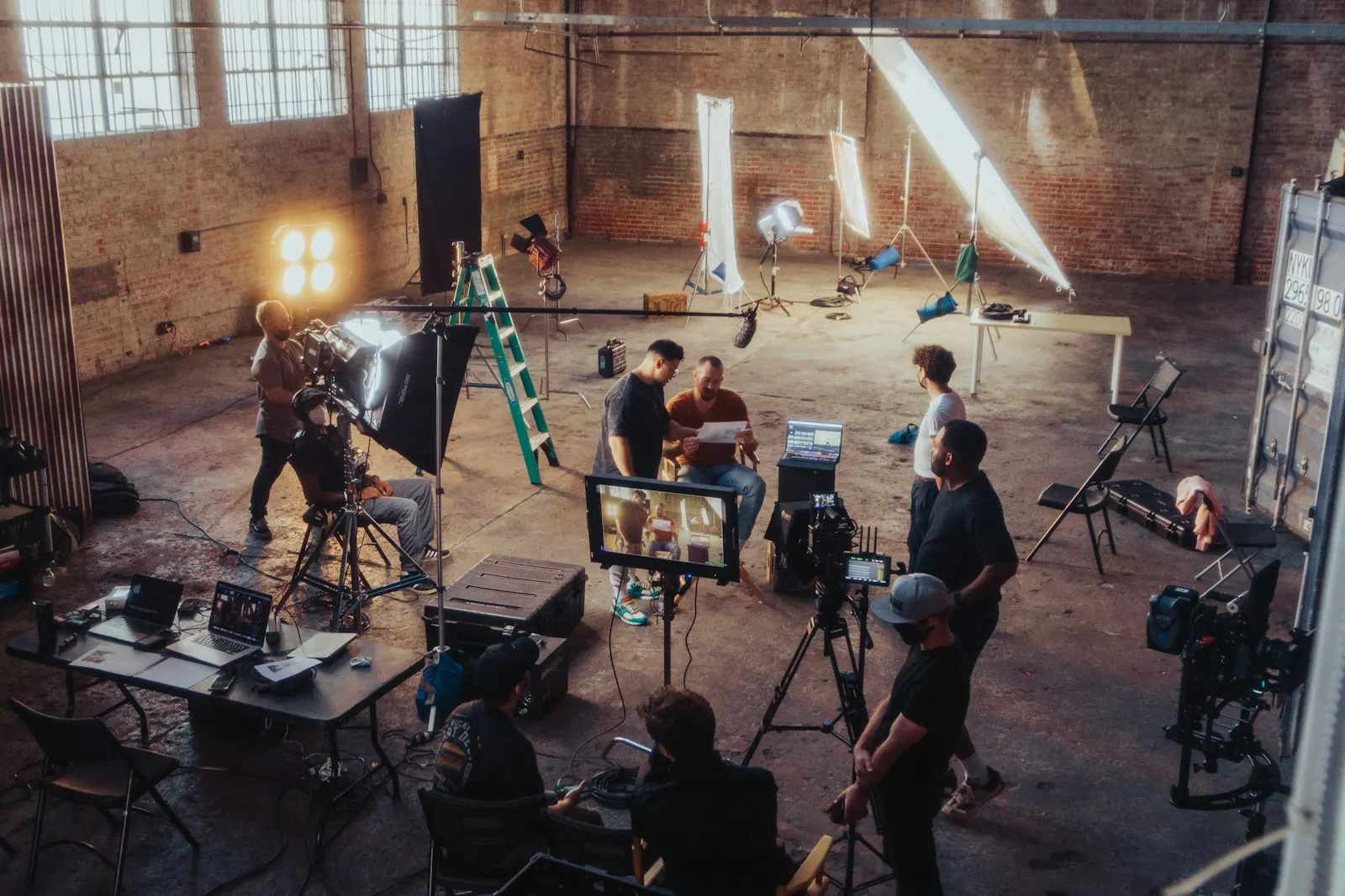 Filmteam mit Kameras, Leuchten und Monitoren bei einem Dreh in einer Halle
