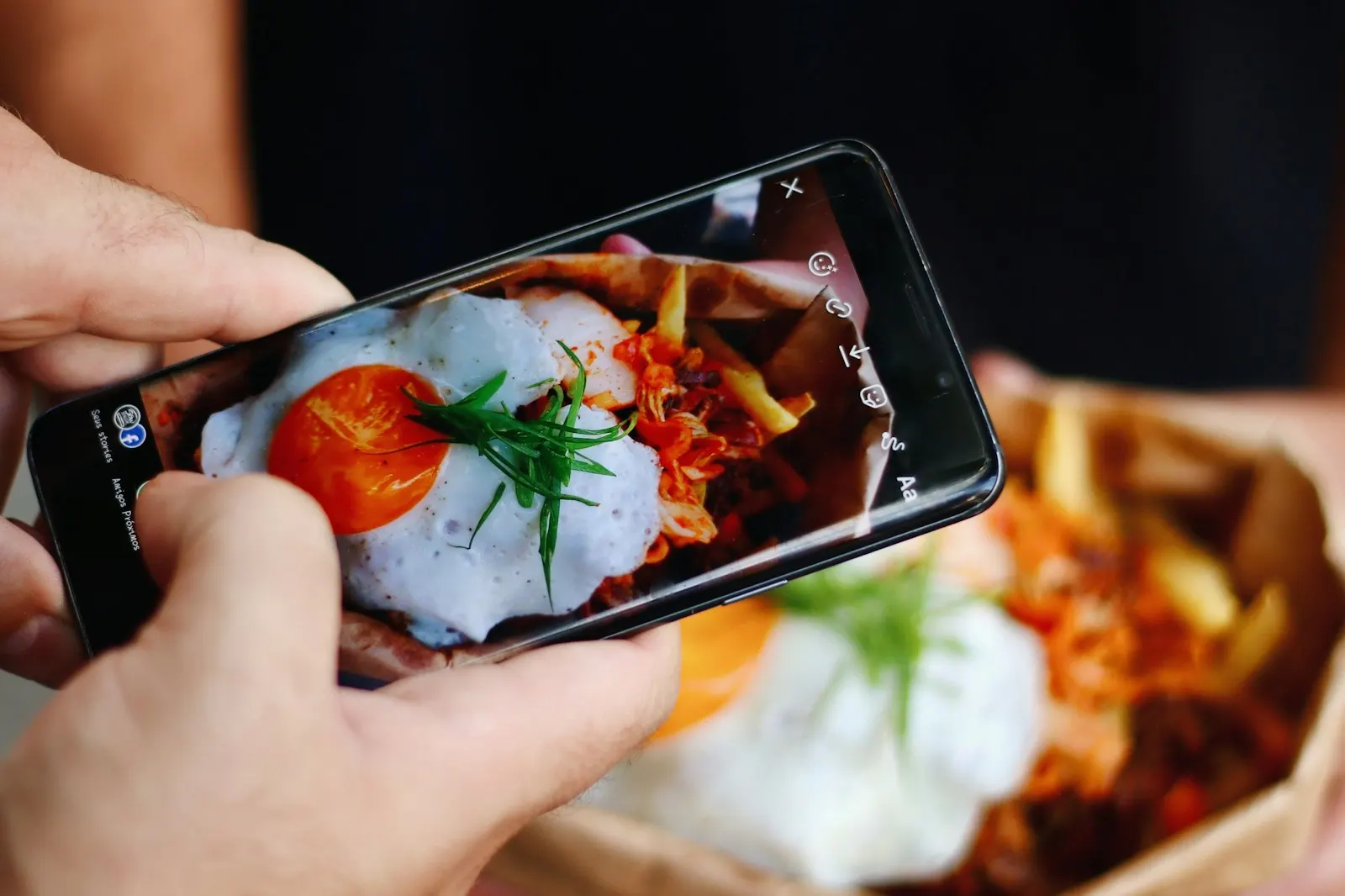 Hand filmt ein angerichtetes Gericht mit dem Smartphone